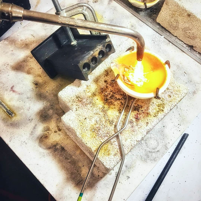 Melting gold in a crucible with a torch on a workbench